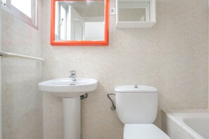 Une salle de bain avec un lavabo, des toilettes et une baignoire, le tout de couleur blanche.