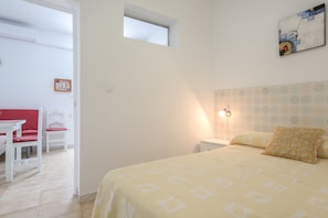A bedroom with a bed, bedside table, lamp, and a window.