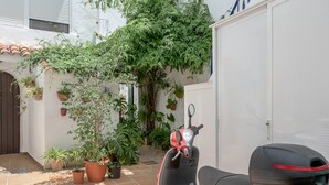 Ein roter Roller steht in einem Innenhof mit Blumentöpfen und einem weißen Gebäude.