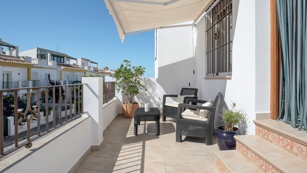 Un balcon agrémenté de meubles d’extérieur, d’une plante en pot et d’un auvent blanc.