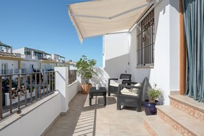 Un balcon agrémenté de meubles d’extérieur, d’une plante en pot et d’un auvent blanc.