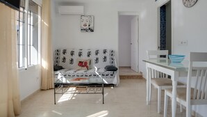 Une pièce comprenant un canapé, une table, des chaises, une horloge et une fenêtre.