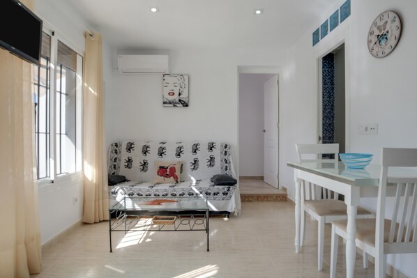 Une pièce comprenant un canapé, une table, des chaises, une horloge et une fenêtre.