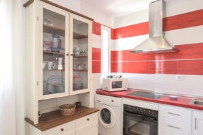 Una cocina con lavadora, microondas, horno y un armario con puertas de vidrio.