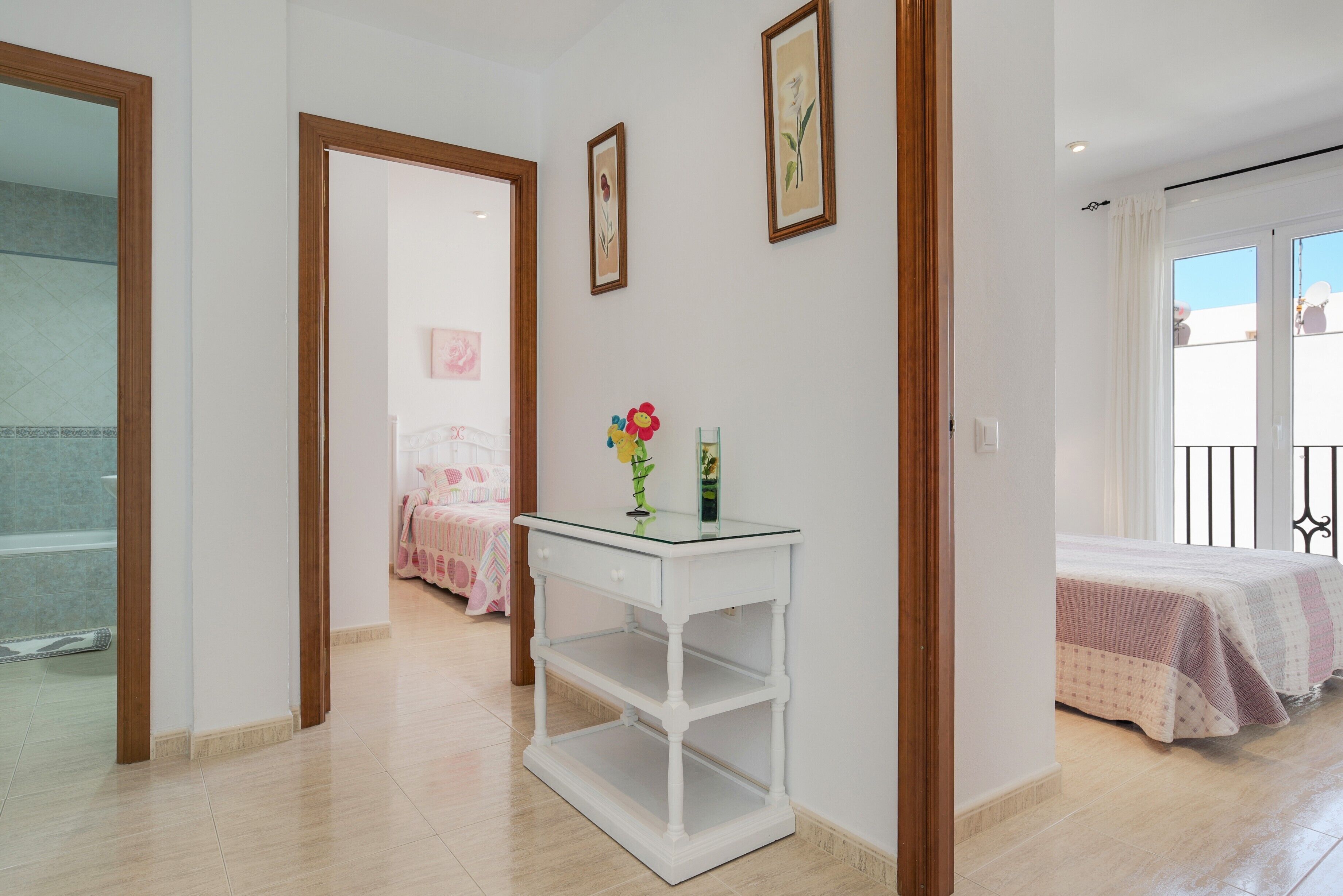 A bedroom with a bed, a white bedside table, and a window.