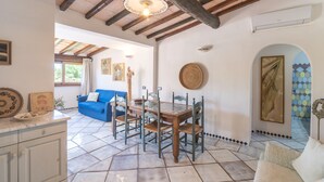 A dining area with a wooden table and chairs, a blue sofa, and a tiled floor. - Villa Ginepro with Private Pool, Sea View, 2 Terraces, Wi-Fi & Air Conditioning (San Teodoro)