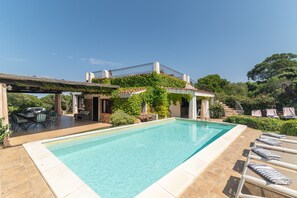 A swimming pool with a pergola and outdoor seating area.