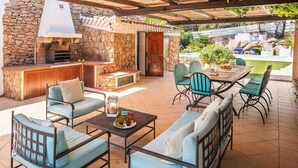 An outdoor patio with stone walls, a grill, and seating. - Villa Ginepro with Private Pool, Sea View, 2 Terraces, Wi-Fi & Air Conditioning (San Teodoro)