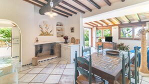 A dining area with a wooden table and chairs, a fireplace, and a view of the outdoors. - Villa Ginepro with Private Pool, Sea View, 2 Terraces, Wi-Fi & Air Conditioning (San Teodoro)