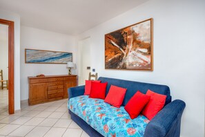 Un salon avec un canapé, un meuble en bois et deux tableaux accrochés au mur.