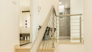 A modern staircase with a metal handrail, a small plant, and a glimpse of a room with a white wall and a door. - Apartment "Happy Dreamer" with Large Pool, Mountain Views & Wi-Fi (Puerto Rico)