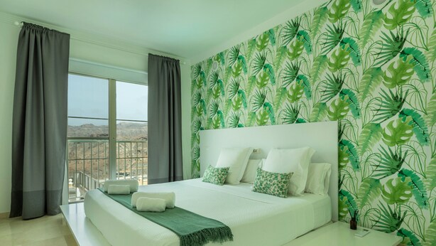 A bedroom with a large bed, a balcony, and a view of the mountains. - Apartment "Happy Dreamer" with Large Pool, Mountain Views & Wi-Fi (Puerto Rico)