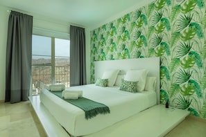 Un dormitorio con una cama grande, un balcón y vistas a las montañas.