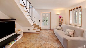 Un salon avec un téléviseur, un canapé et un escalier.
