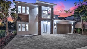 A modern two-story house with a brick facade, large windows, and a garage.