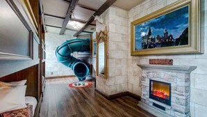 A hallway with a fireplace, a large mirror, and a painting of a castle.
