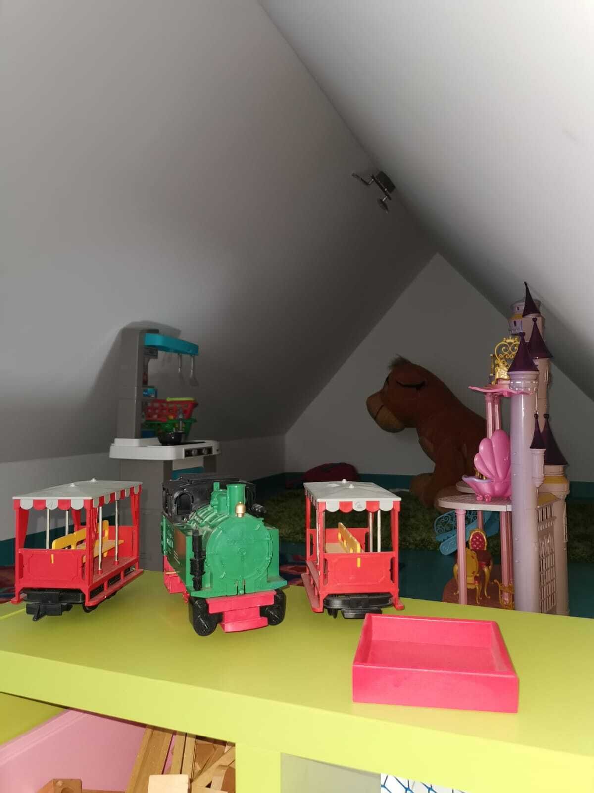 Zona de juegos infantiles con trenes de juguete y una estructura de castillo.
