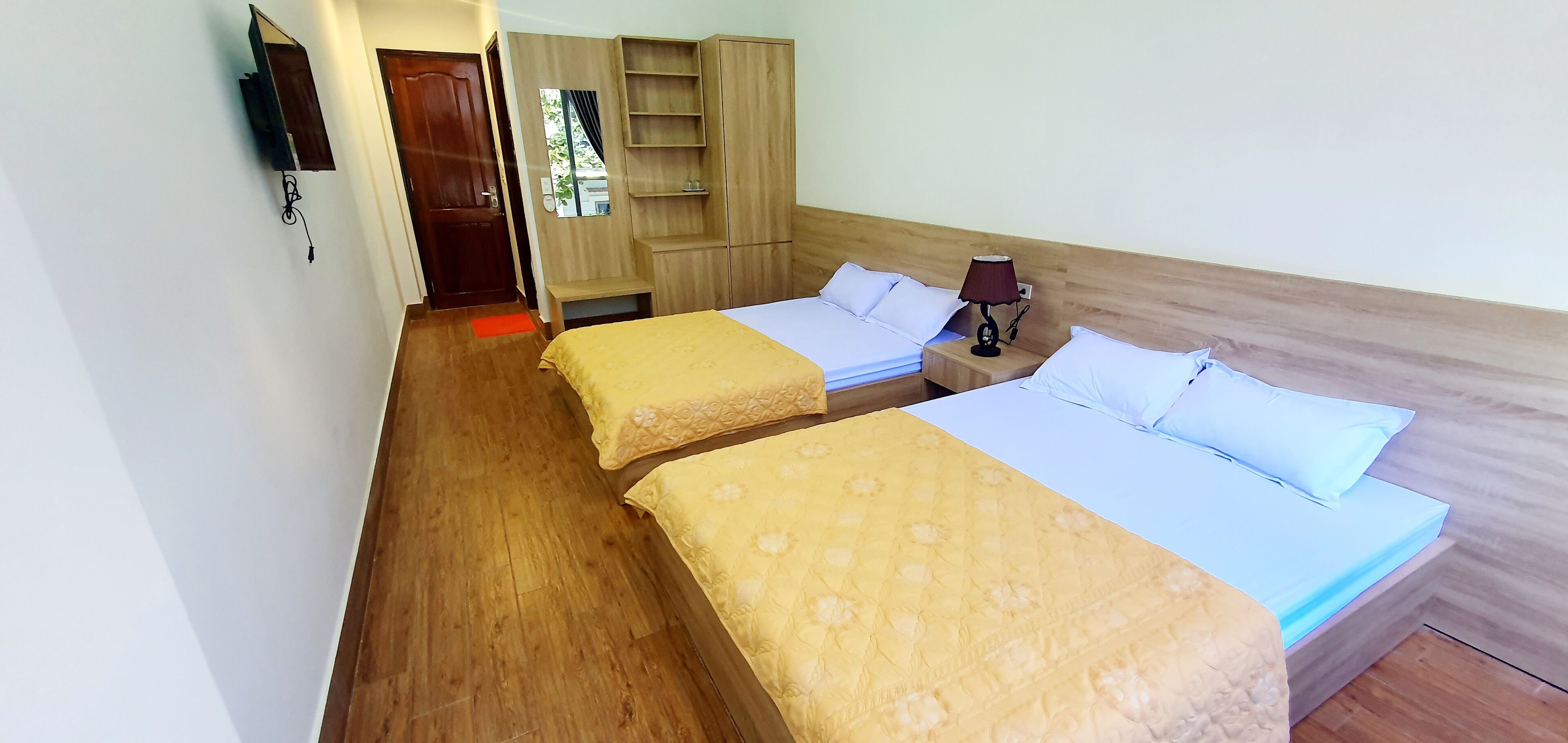 Une chambre d’hôtel avec deux lits, un plancher en bois, une armoire, une télévision et une lampe de chevet.