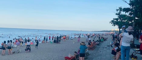 Une plage bondée où les gens se prélassent au soleil et se baignent.