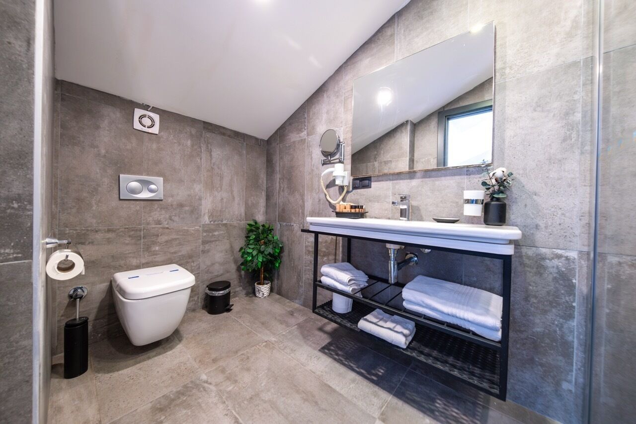 Un baño moderno con inodoro, lavabo, espejo y toallero.