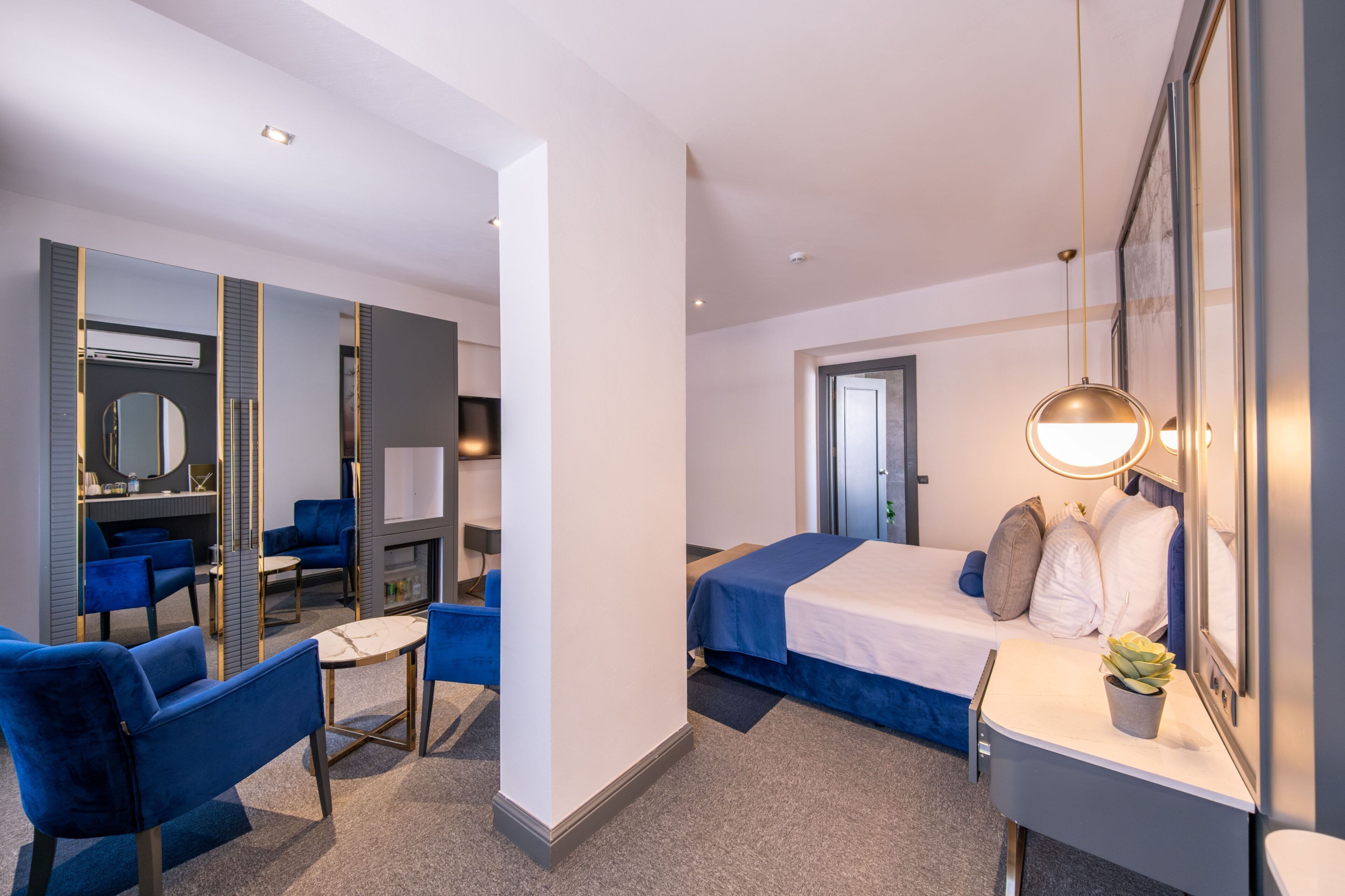 Una habitación de hotel moderna con cama, escritorio, silla, espejo y una mesita.