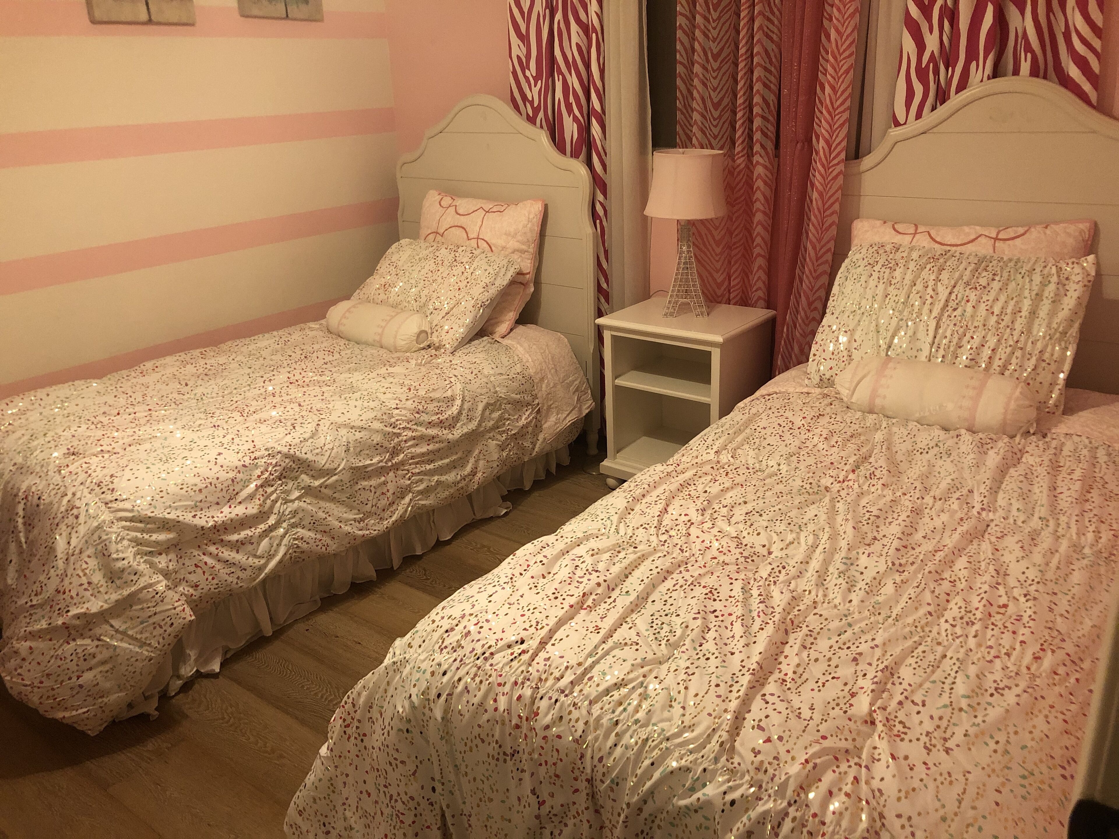 Un dormitorio doble con dos camas individuales, una mesita de noche y una lámpara.