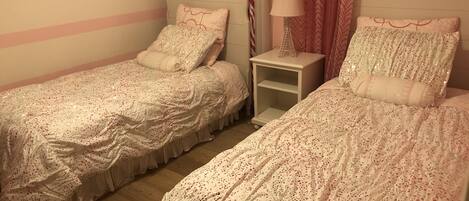 Un dormitorio doble con dos camas individuales, una mesita de noche y una lámpara.