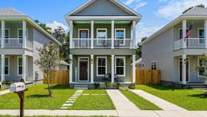 A two-story residential building with a front porch, a mailbox, and a small garden.