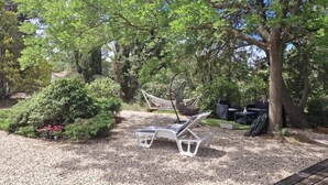 Un jardin avec deux chaises longues, un hamac et une petite table.