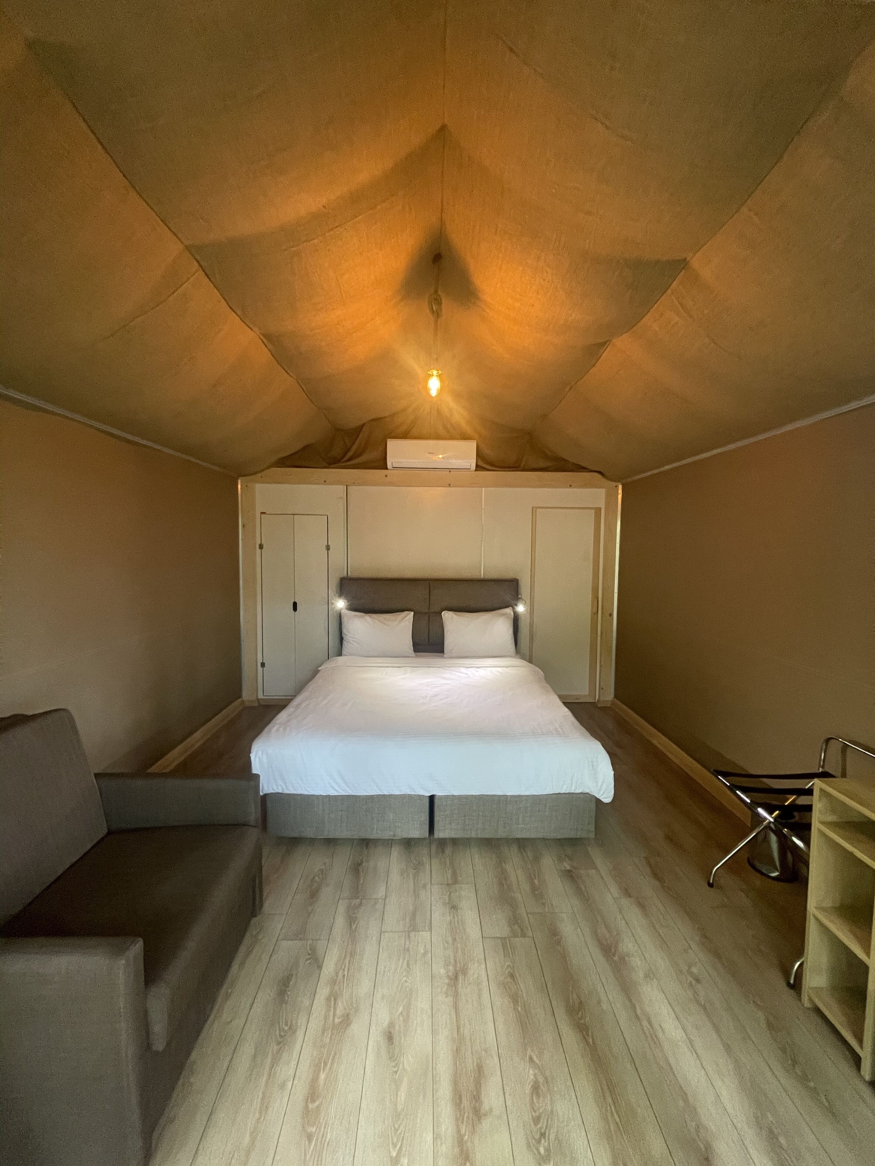 A bedroom with a bed, a sofa, a chair, and a small table.