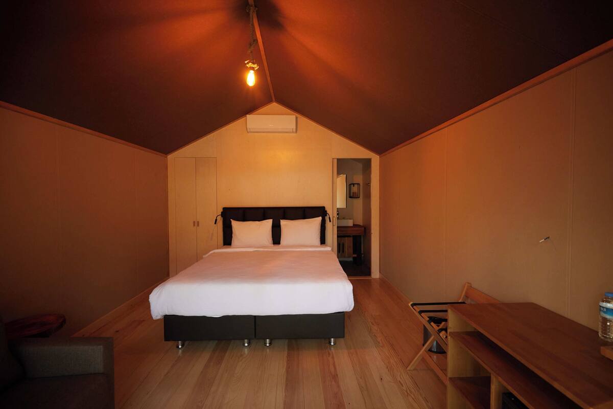 A bedroom with a large bed, a wooden desk, and a chair.