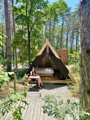 A wooden tent with a bed inside, surrounded by a forest. - Longosphere Glamping (Demirköy)