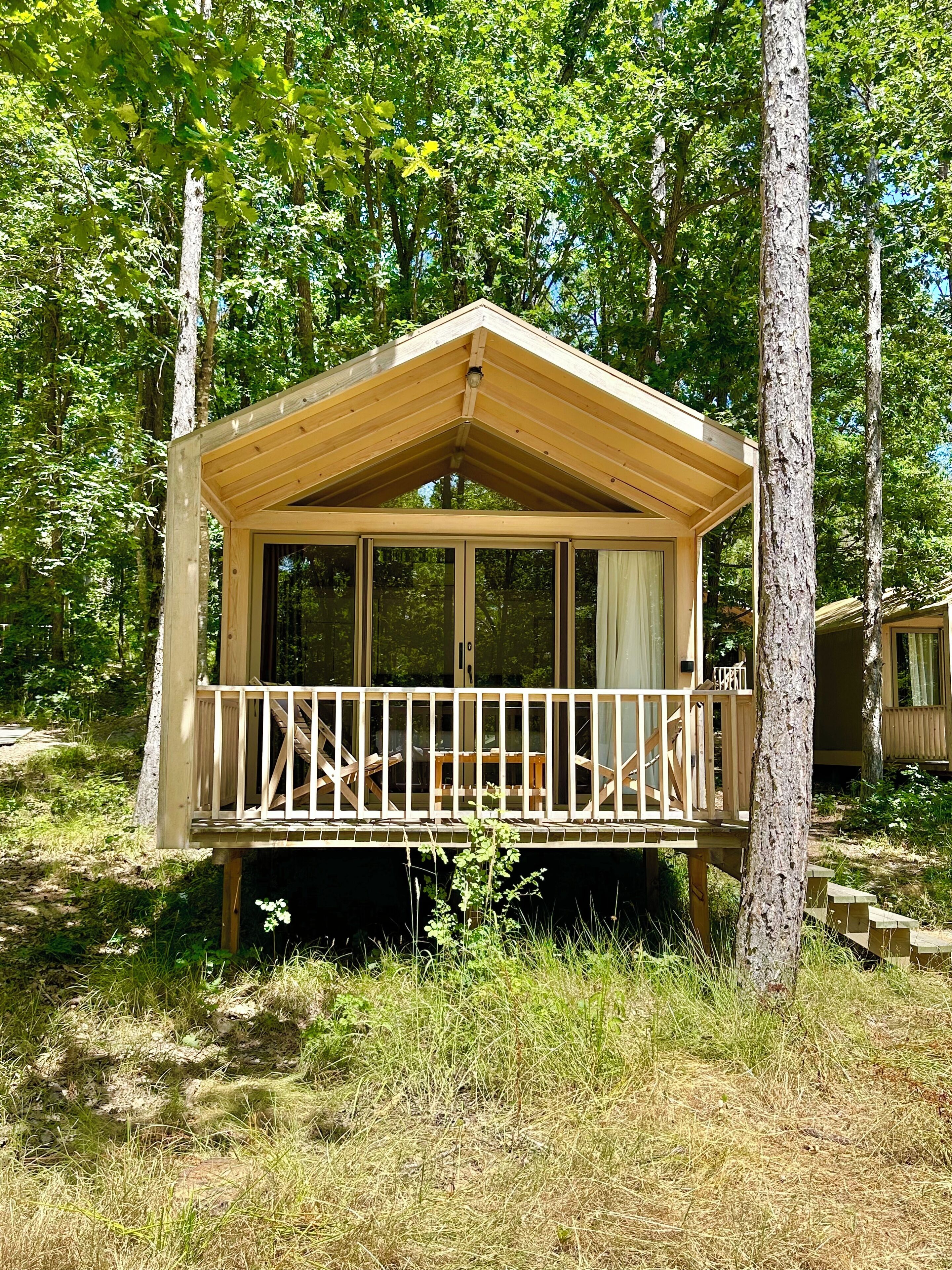Eine Holzhütte mit Balkon, umgeben von Bäumen.