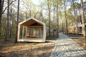 A wooden cabin with a glass enclosure, a stone pathway, and a forested backdrop. - Longosphere Glamping (Demirköy)