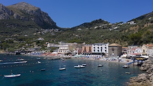 A coastal town with buildings along the waterfront, a pier, and boats in the water. - Apartment Giove With Sea View & Pool (Nerano)