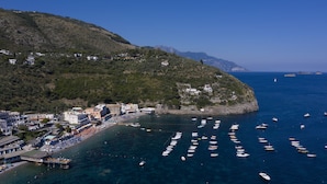 A coastal town with a marina filled with boats, a beach area, and buildings on a hillside. - Apartment Giove With Sea View & Pool (Nerano)