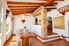 A dining area with a wooden table, chairs, and a stone pillar.