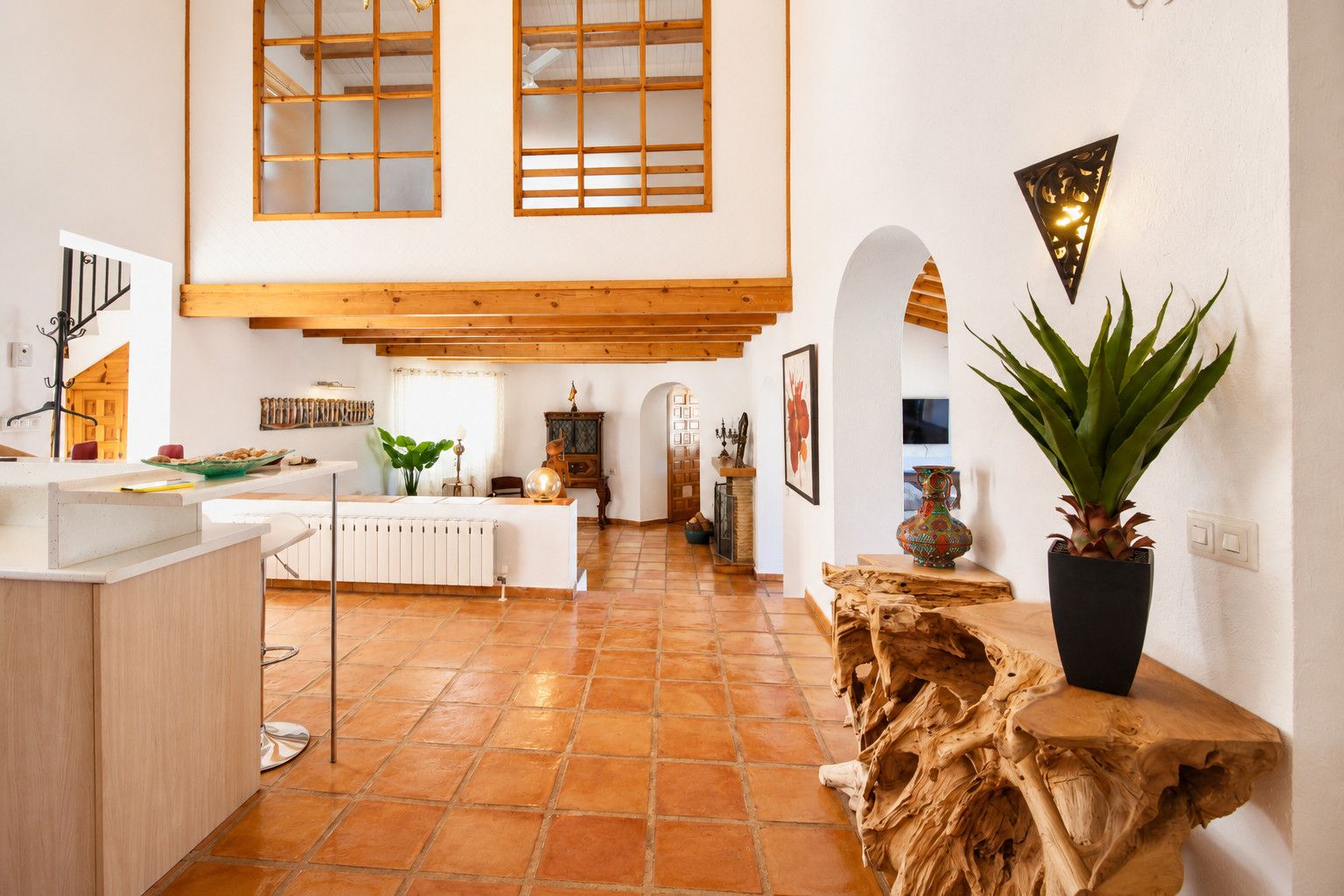 A spacious kitchen with a central island, wooden beams, and a large window.