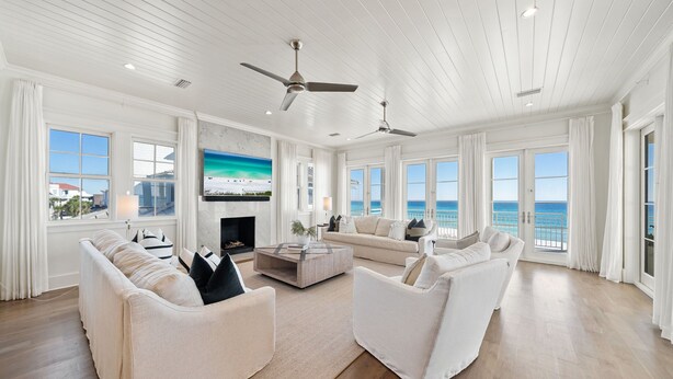 A spacious living room with a large window overlooking the ocean, a fireplace, and two white sofas. - Stunning Retreat w/Gulf views, heated pool, beach access, and bikes. Sleeps 12! (Seagrove Beach)