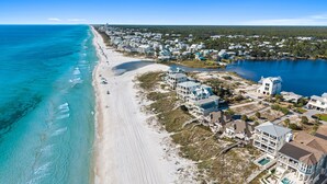 An aerial view of a coastal area with a beach, a large body of water, and residential buildings. - Stunning Retreat w/Gulf views, heated pool, beach access, and bikes. Sleeps 12! (Seagrove Beach)