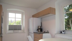 Una cocina moderna con refrigerador empotrado, cafetera y un radio en el alféizar de la ventana.