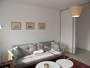 A modern living room with a grey sofa, two white side tables, and a hanging light fixture. - Holiday apartment Rudolph - Villa Gertrud *** approx. 10 minutes walk to the Baltic Sea beach *** (Zinnowitz)