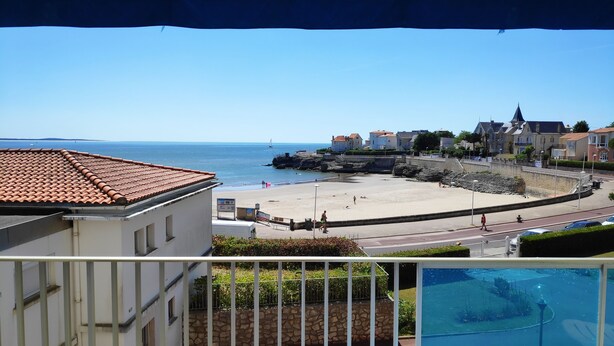 En kustvy med en strand, byggnader och en swimmingpool.