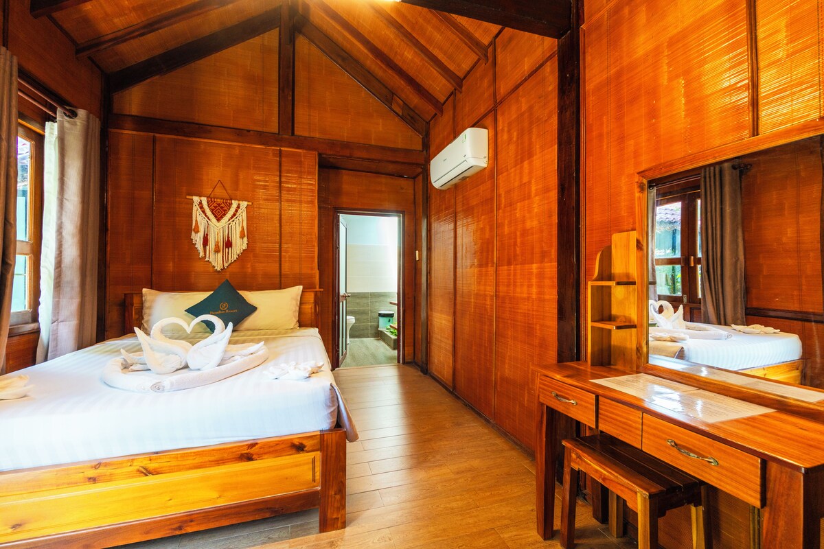 A wooden room with a bed, a desk, and a mirror.