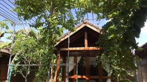 A wooden gazebo with a sloped roof, surrounded by lush greenery and a metal fence. - Green Bungalow Phu Quoc (Phu Quoc)