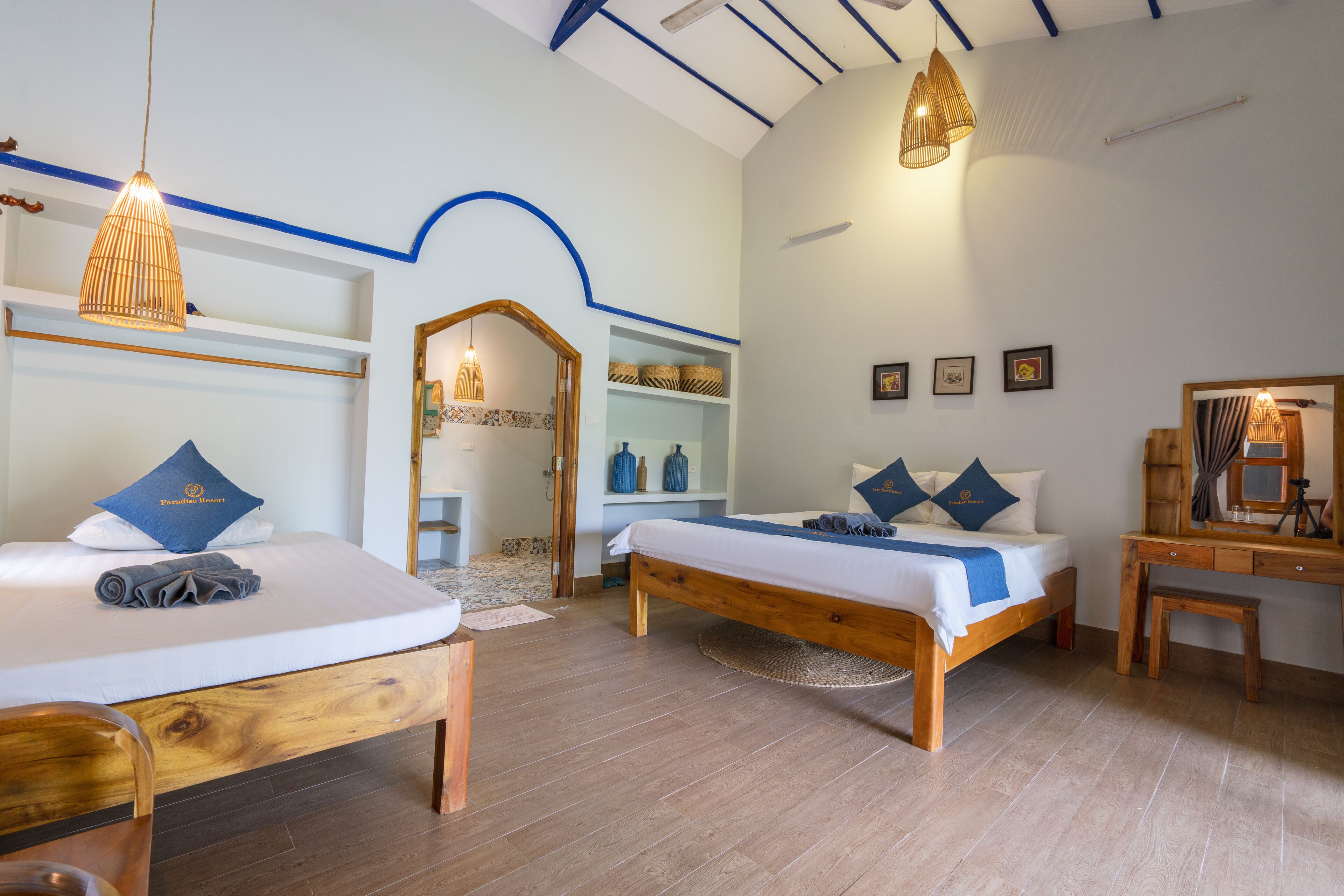 Une chambre d’hôtel avec deux lits, des meubles en bois et un bureau avec un miroir.