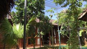 A courtyard with a wooden house, a metal pergola, and various trees. - Green Bungalow Phu Quoc (Phu Quoc)