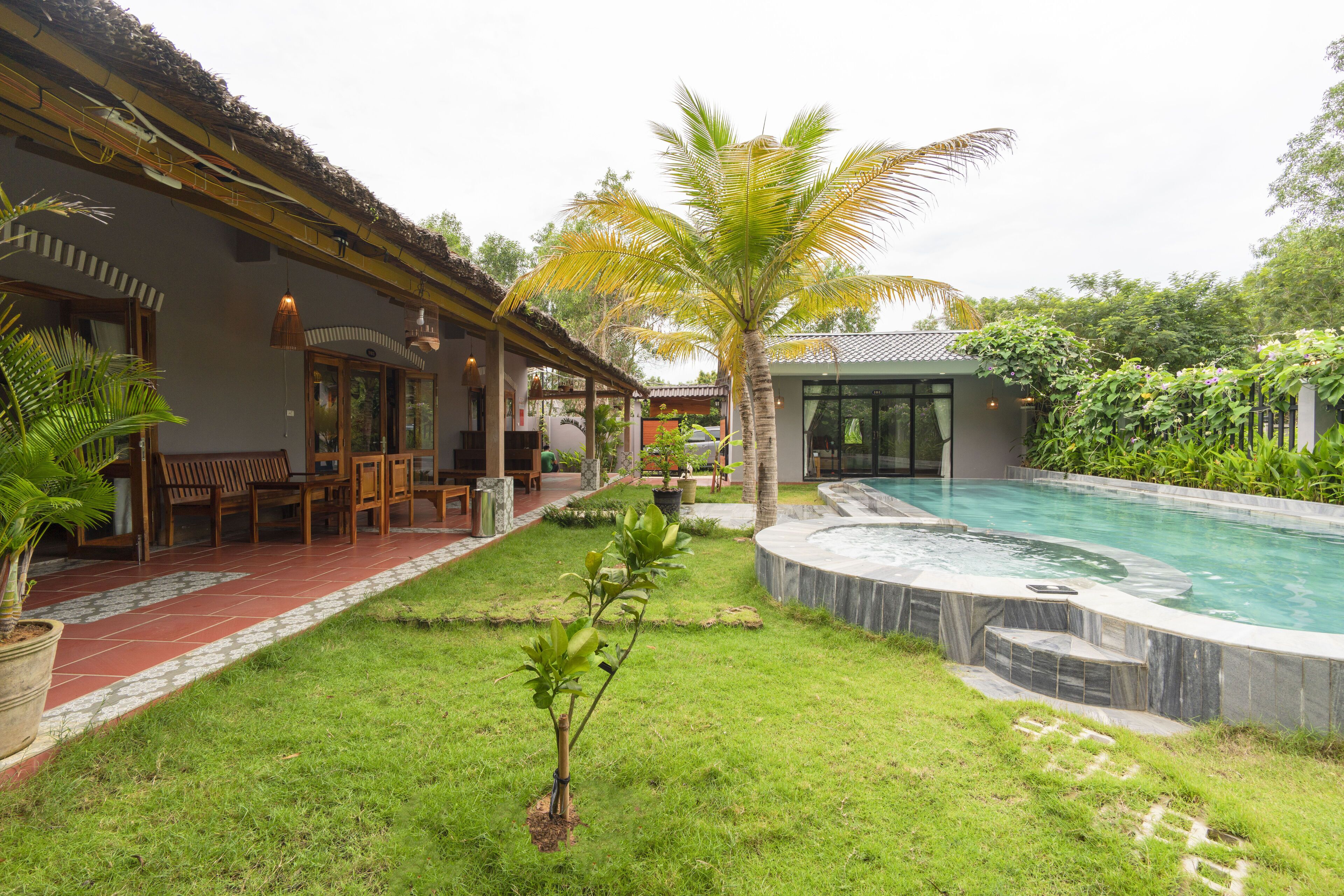 A pool area with a palm tree, a wooden deck, and a building with a tiled roof.