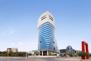 A modern, multi-story building with a distinctive curved top and a large glass facade.