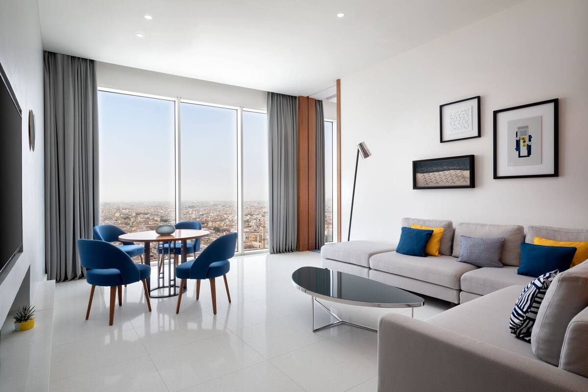 Una sala de estar moderna con sofá, sillones, una mesa de centro y obras de arte en la pared.